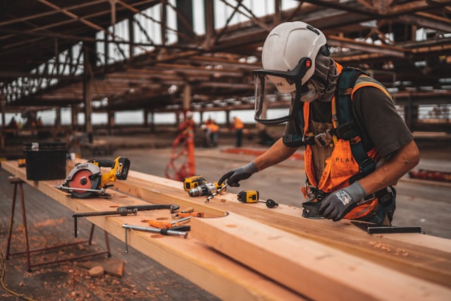 Hombre con casco trabajando con madera y herramaientas - Foto por Jeriden Villegas
